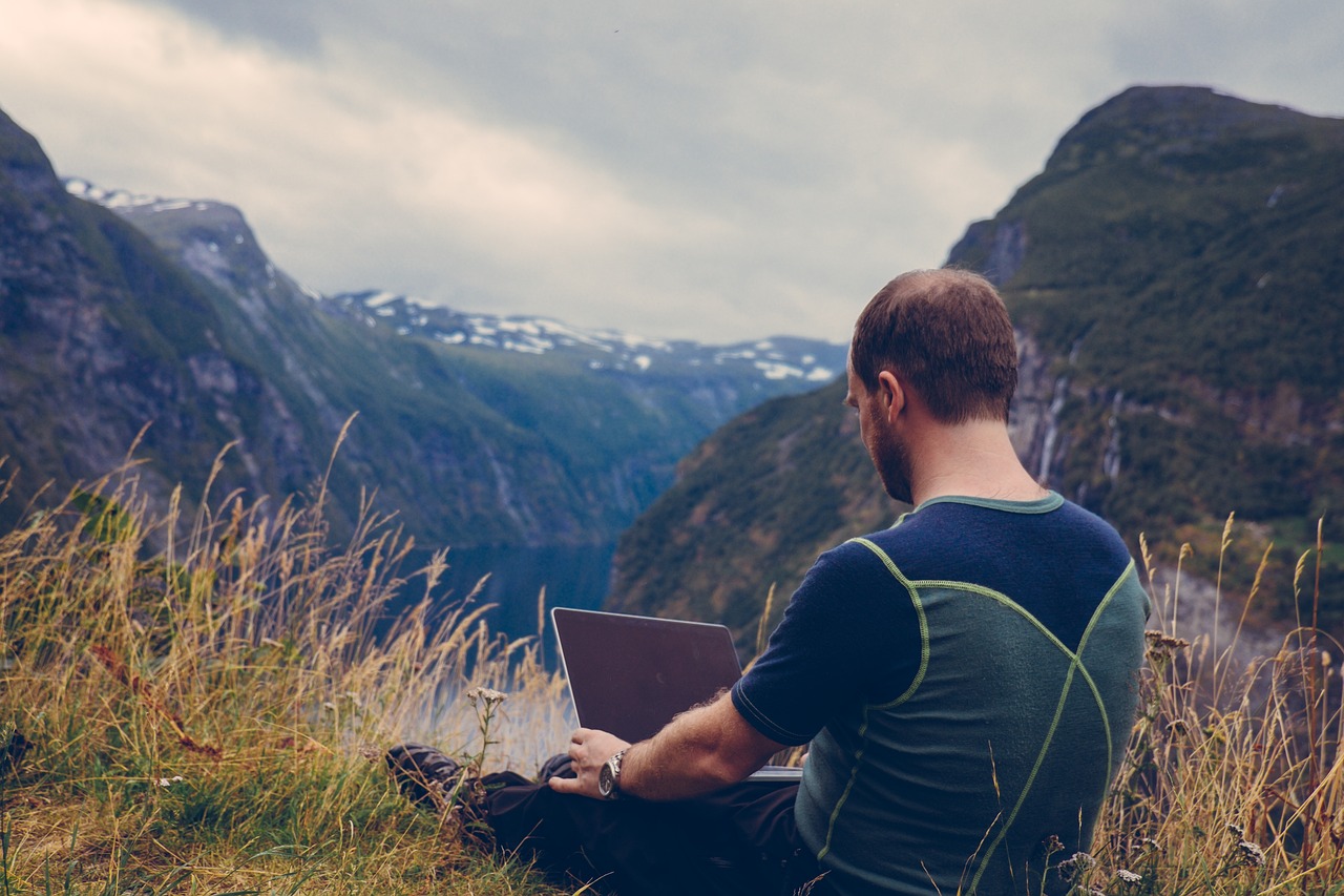 Bild von einem Digitalnomaden mit Laptop vor imposanter Naturkulisse